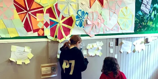 Two children standing in front of a wall covered in geometric artwork.