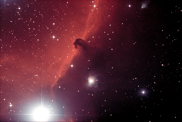 An image of a galaxy with red and black colour nuances, and white shining stars.