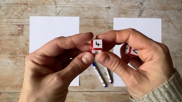 A person holding a dice showing a number 2 and a number 4.