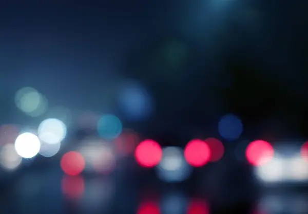 Bokeh effect image with a dark blue background and out of focus dots in white, pink and blue.